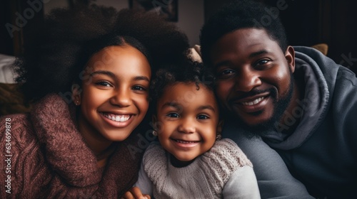 picture of a happy young African American family with little children sitting lounging on the sofa, cuddling lying down,
