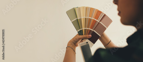 Obraz na płótnie Woman choosing color using swatch catalog standing near wall.