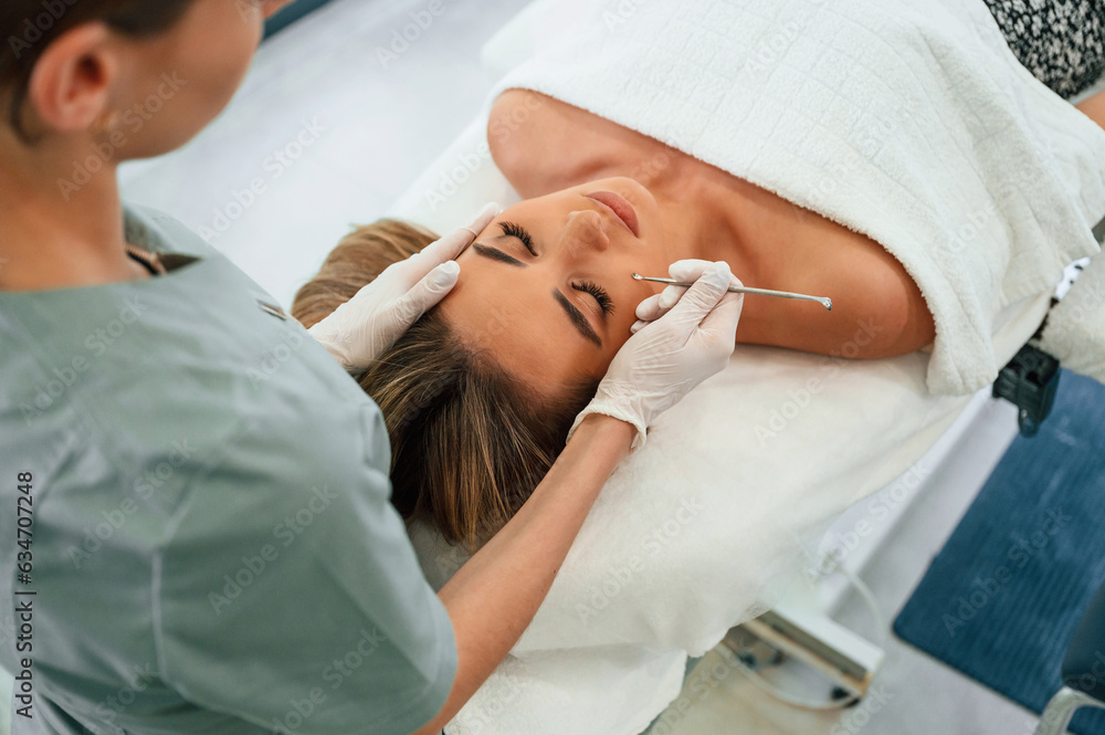 With cosmetic spoon. Woman face getting facial care by beautician hands at spa salon With cosmetic spoon. Woman face getting facial care by beautician hands at spa salon