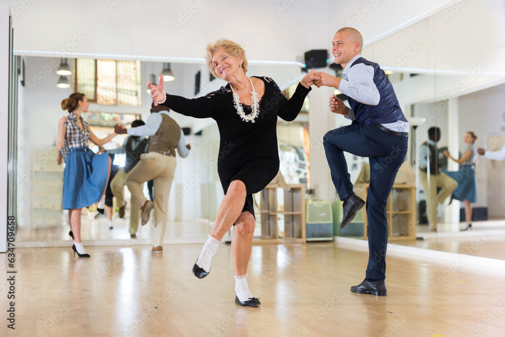 Mature woman learning to dance lindy hop with younger man