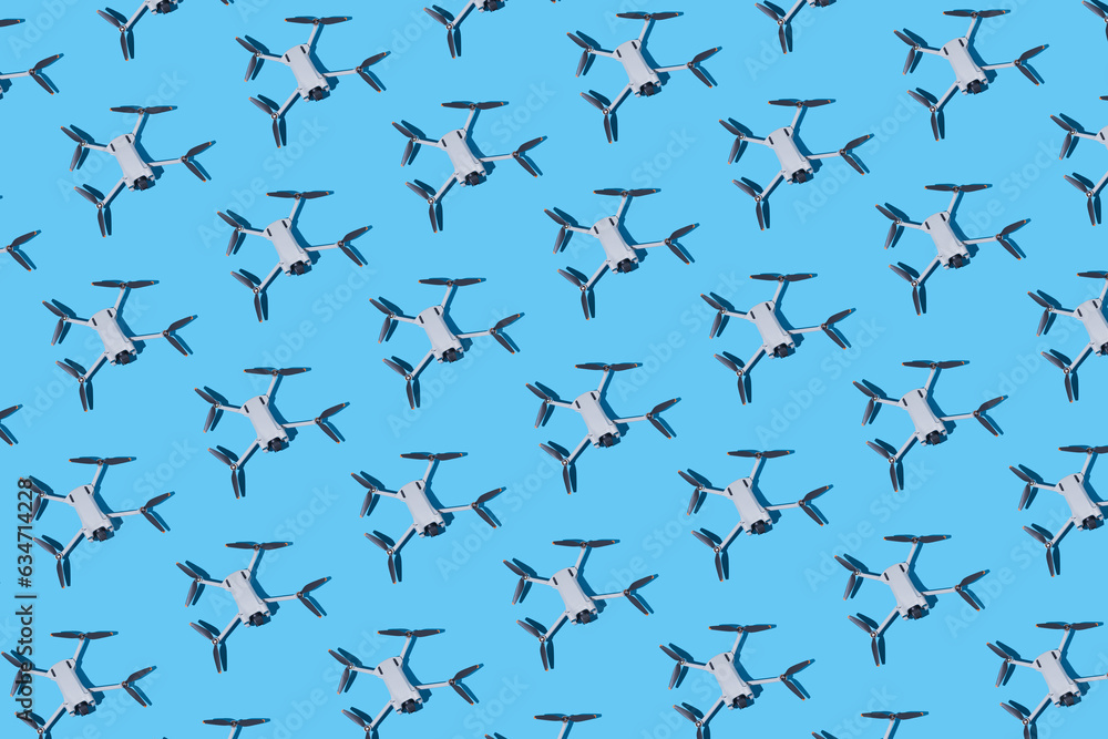 Pattern of gray drones, with photo and video cameras, and dark propellers on a blue background. UAV, fly, spy, altitude, unmanned, technology and futuristic concept. Pattern of gray drones, with photo and video cameras, and dark propellers on a blue background. UAV, fly, spy, altitude, unmanned, technology and futuristic concept.