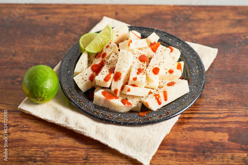 Mexican snack yam bean also called Jicama with chili powder and chamoy sauce photo