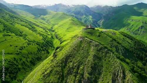 kazbegi trinity church among the green mountains view from a flying drone - stock video georgia stepantsminda photo