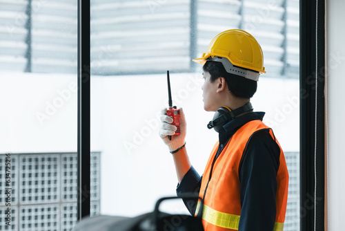 Young Asian engineer talking radio walkie talkie to operate and control the worker employee to build construction.