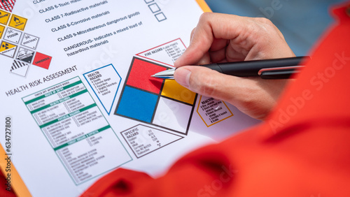 Fotografie A safety engineer is using pen to rating the health risk assessment level of chemical hazardous material in the paperwork form