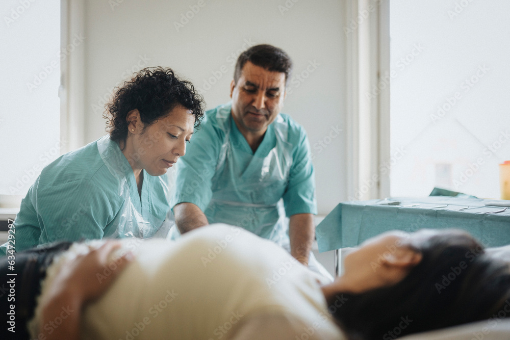 Male and female surgeons examining patient in hospital Male and female surgeons examining patient in hospital