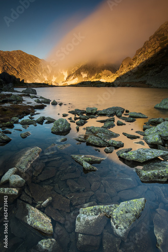 Lake in the mounstains with peaks in background luminated by sunrise photo