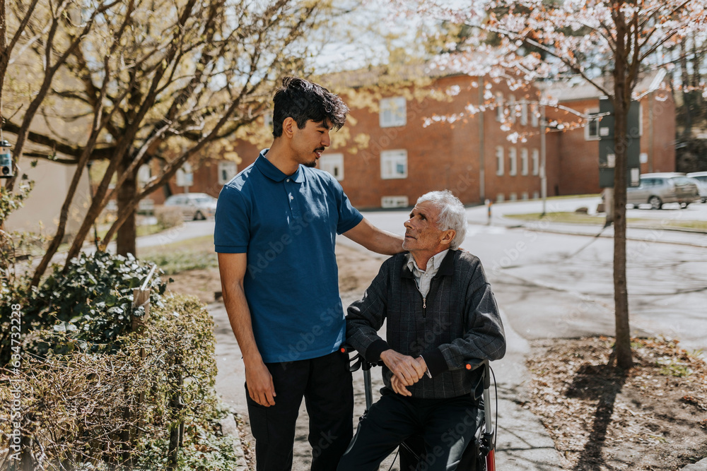 Male caregiver with hand on shoulder of senior man sitting on walker Male caregiver with hand on shoulder of senior man sitting on walker