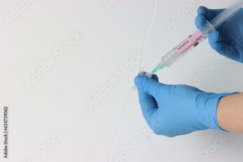 Professional wearing gloves injecting ephedrine into a intravenous set. photo