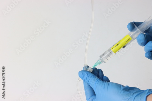 Professional wearing gloves injecting Etomidate into a intravenous set. photo