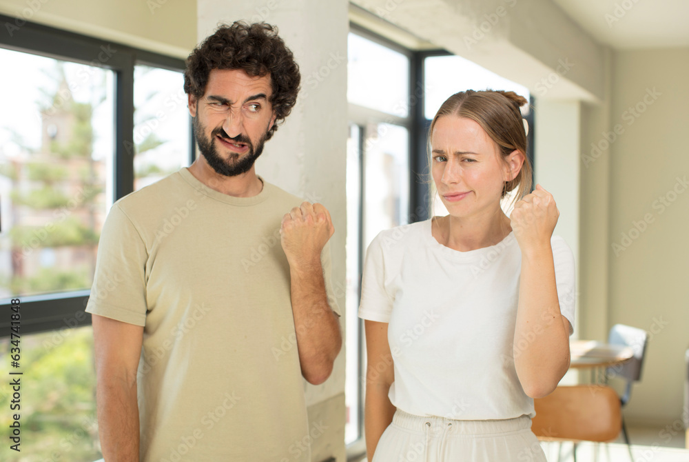 Fototapeta premium young adult couple looking confident, angry, strong and aggressive, with fists ready to fight in boxing position