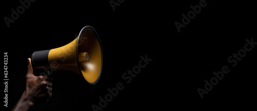 Generative AI, golden megaphone in hand on a empty black background, panoramic image with copy space