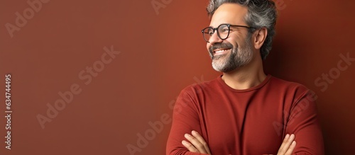 A mature and confident man feeling joyful and optimistic gazes up with arms crossed