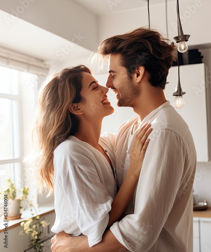 Copy space available for playful young couple having fun and embracing in kitchen side view photo