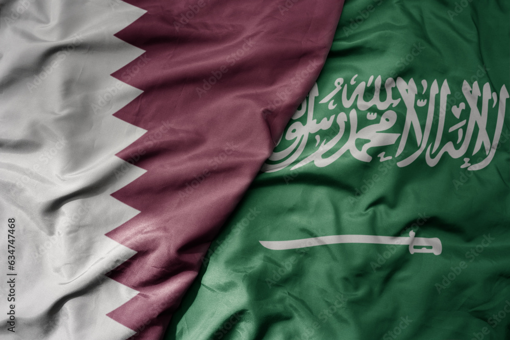 big waving realistic national colorful flag of qatar and national flag of saudi arabia .
