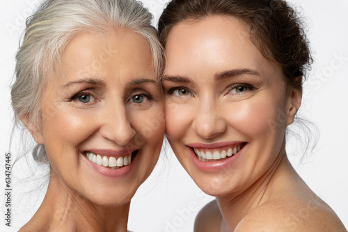 Close-up portrait of two women of different ages taking care of their skin, looking at the camera with a smile