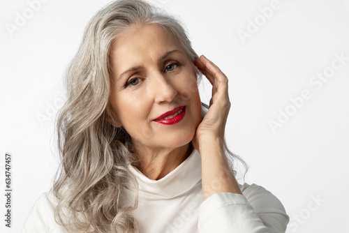 Beautiful senior woman with gray hair and nice makeup. A mature woman is nursing herself..