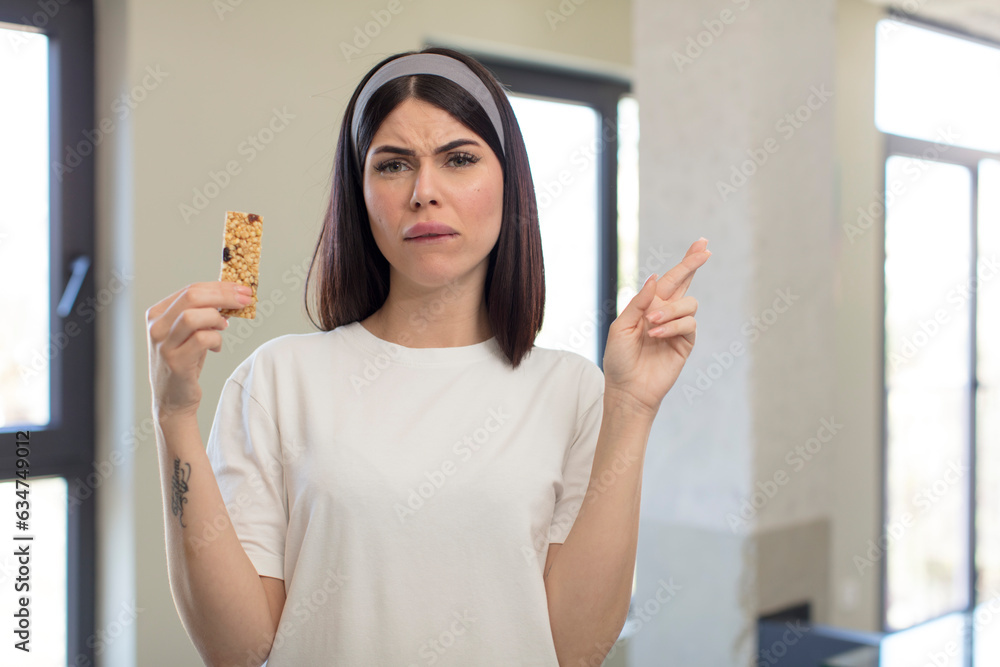 pretty young woman crossing fingers and hoping for good luck. fitness cereal bar concept pretty young woman crossing fingers and hoping for good luck. fitness cereal bar concept