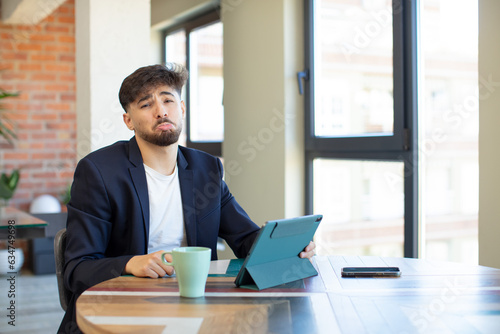 young handsome man feeling sad and whiney with an unhappy look and crying. touch screen pad concept photo