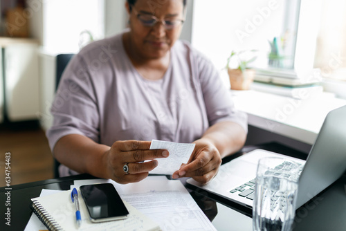 Photos Selective focus on black female hands holding utility bill or paycheck sitting i