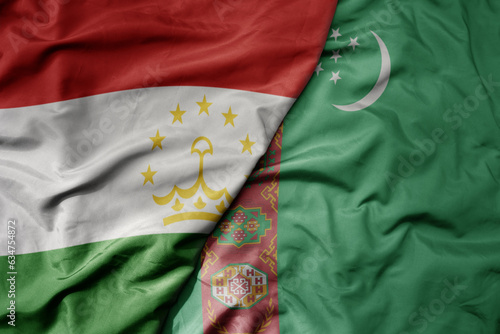 big waving realistic national colorful flag of tajikistan and national flag of turkmenistan .