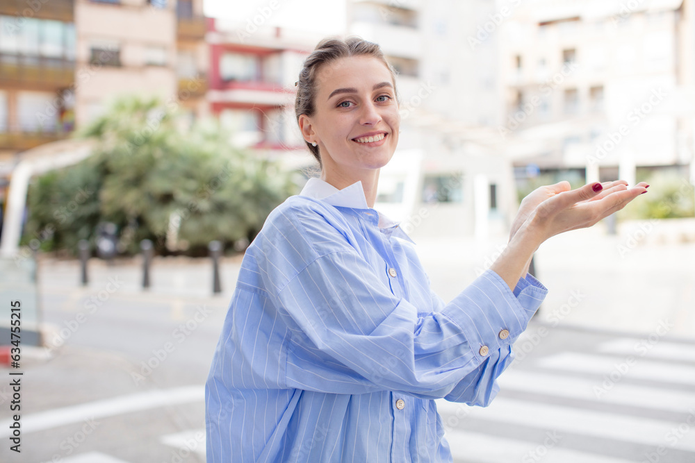 Fototapeta premium pretty woman feeling happy and cheerful, smiling and welcoming you, inviting you in with a friendly gesture