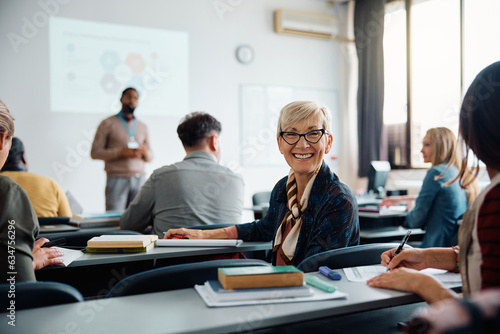 Happy mature woman on education training class in lecture hall looking at camera.