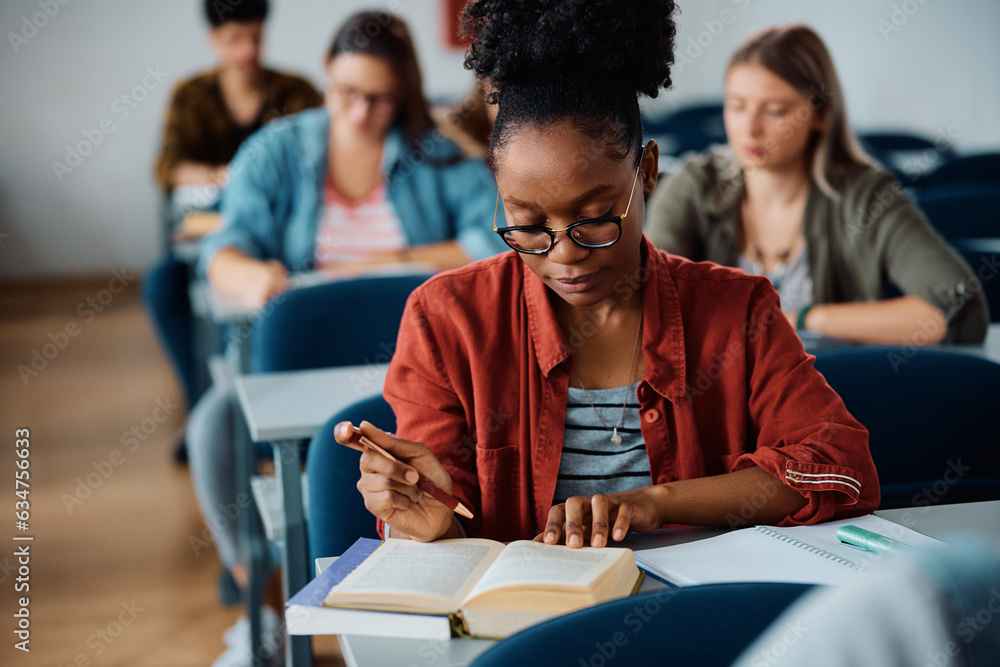 Female African American university student learning in lecture hall. Female African American university student learning in lecture hall.