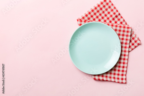 Top view on colored background empty round blue plate on tablecloth for food. Empty dish on napkin with space for your design