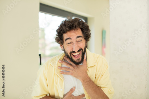 young crazy bearded man laughing out loud at some hilarious joke, feeling happy and cheerful, having fun