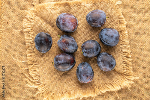 Several sweet ripe plums on a jute cloth, macro, top view.