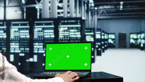 Experienced IT developer in server farm housing high end racks capable of quickly and efficiently performing complex computations and data analysis, using mockup laptop to patch up bugs