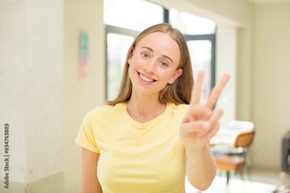 pretty blond woman smiling and looking happy, carefree and positive, gesturing victory or peace with one hand pretty blond woman smiling and looking happy, carefree and positive, gesturing victory or peace with one hand