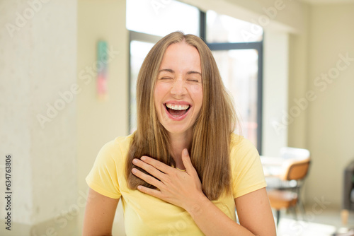 pretty blond woman laughing out loud at some hilarious joke, feeling happy and cheerful, having fun