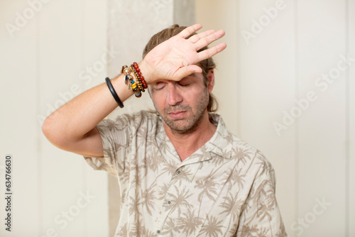 young blond adult man looking stressed, tired and frustrated, drying sweat off forehead, feeling hopeless and exhausted