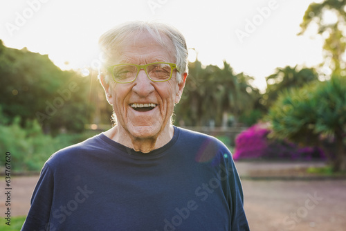 Fit senior man smiling on camera during sunset time at city park after yoga lesson