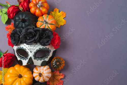 Fototapeta Naklejka Na Ścianę i Meble -  Day of the dead Mexican and Halloween holiday concept. Sugar skull mask, pumpkin and party decorations on purple background. Top view, flat lay