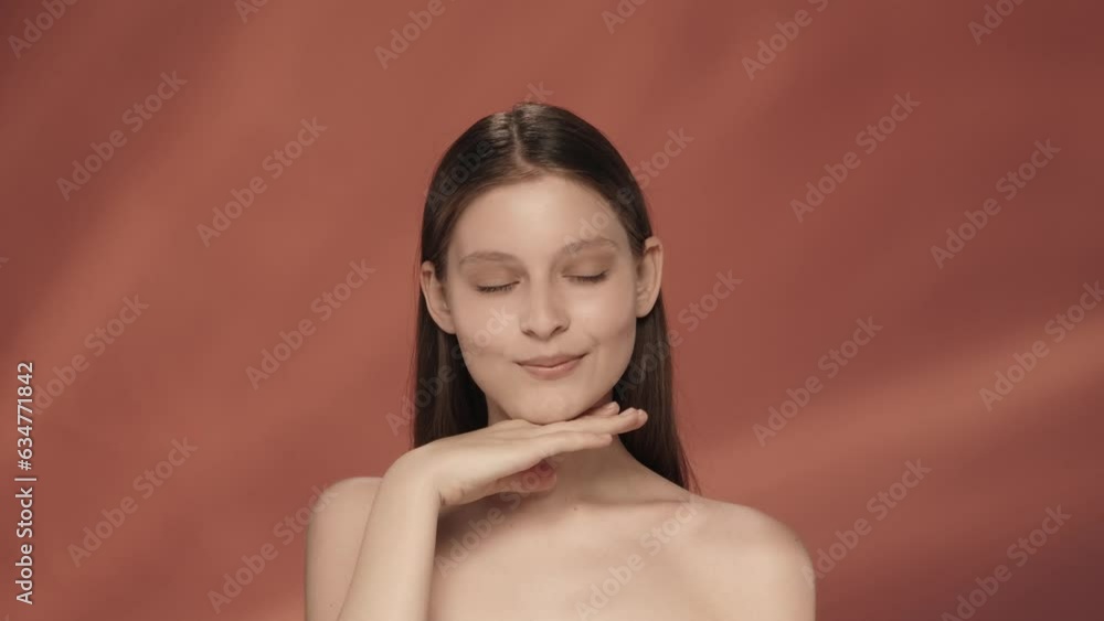 A young woman demonstrates clear skin and regular facial features. Portrait of a seminude woman in a studio on a red background close up. Facebuilding. The concept of natural beauty, cosmetology. A young woman demonstrates clear skin and regular facial features. Portrait of a seminude woman in a studio on a red background close up. Facebuilding. The concept of natural beauty, cosmetology.