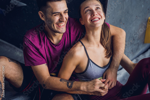 A strong couple of climbers against an artificial wall with colorful grips and ropes.