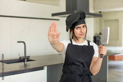young woman looking serious showing open palm making stop gesture. chef concept