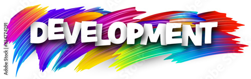 Development paper word sign with colorful spectrum paint brush strokes over white.
