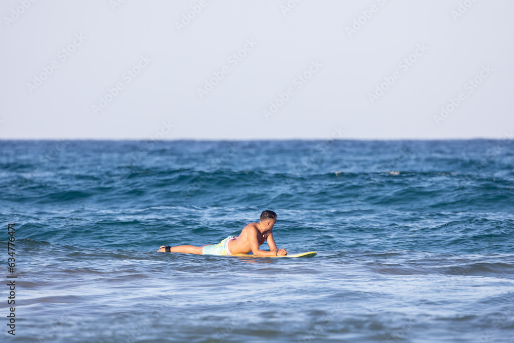 man lying on the surfboard in the sea man lying on the surfboard in the sea
