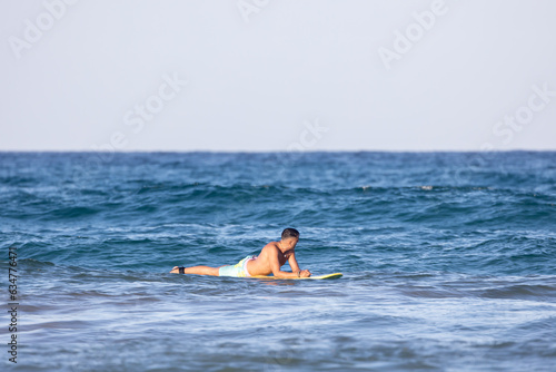 man lying on the surfboard in the sea © OneLoveOnePhoto