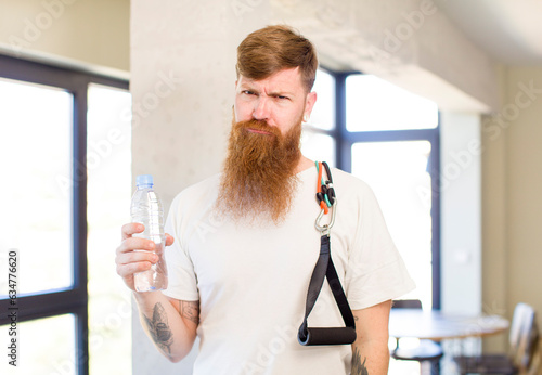red hair man feeling sad and whiney with an unhappy look and crying with a water bottle. fitness concept