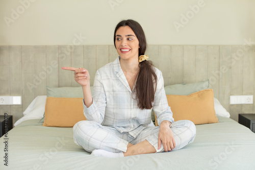 pretty young model smiling cheerfully, feeling happy and pointing to the side. rest and nightwear concept