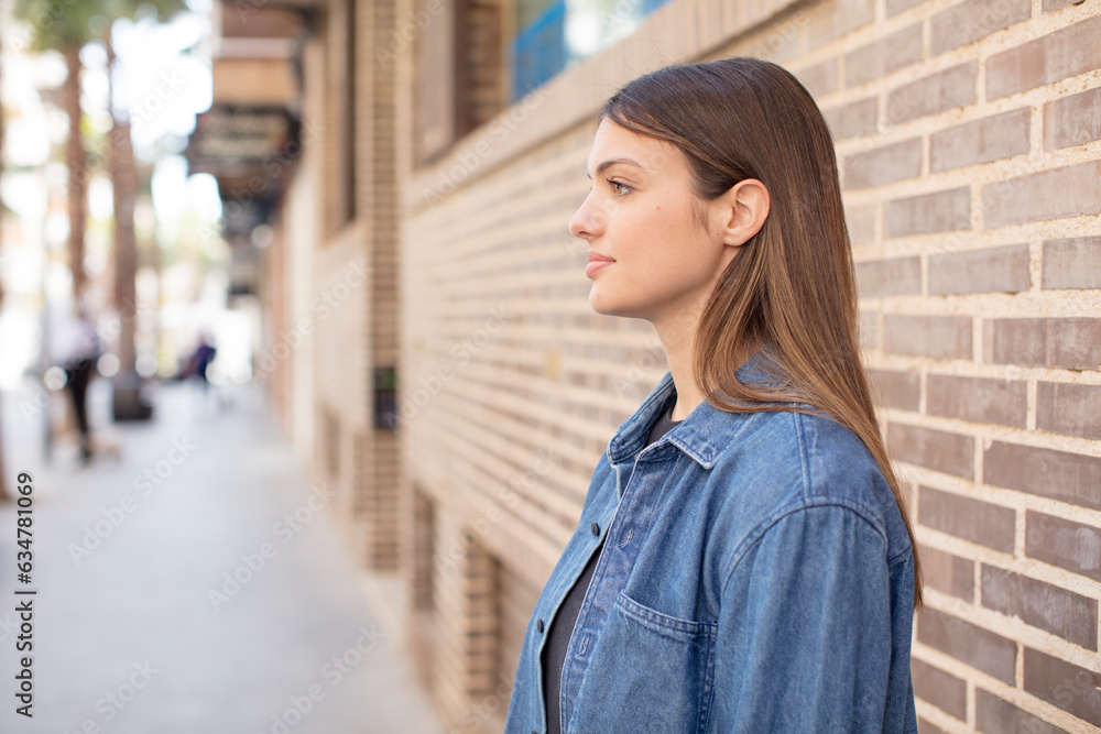 young pretty woman on profile view looking to copy space ahead, thinking, imagining or daydreaming young pretty woman on profile view looking to copy space ahead, thinking, imagining or daydreaming
