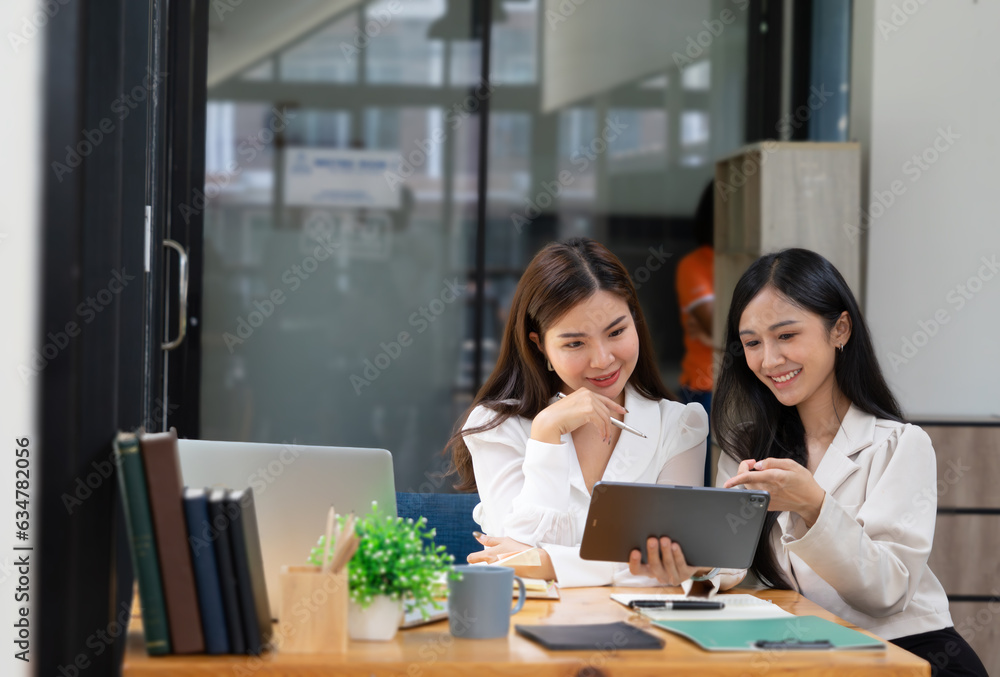 Two happy young women discussing business while working together at the creative office Two happy young women discussing business while working together at the creative office