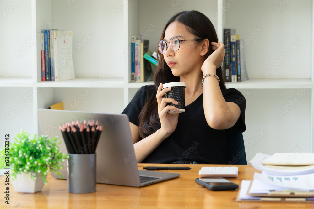 Businesswoman holding a cup of coffee and taking a break from working on her computer. Businesswoman holding a cup of coffee and taking a break from working on her computer.