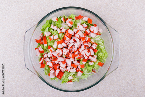Fresh salad with crab sticks, lettuce and napa cabbage close up in glass bowl . Macro shot. Top view.