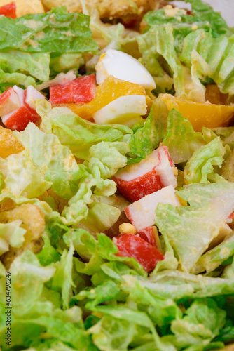 Salad with crab sticks, tomatoes, napa cabbage, eggs, lettuce and croutons close up. Macro shot.